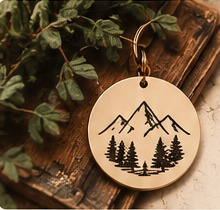 A mountain and trees engraved on a round charm